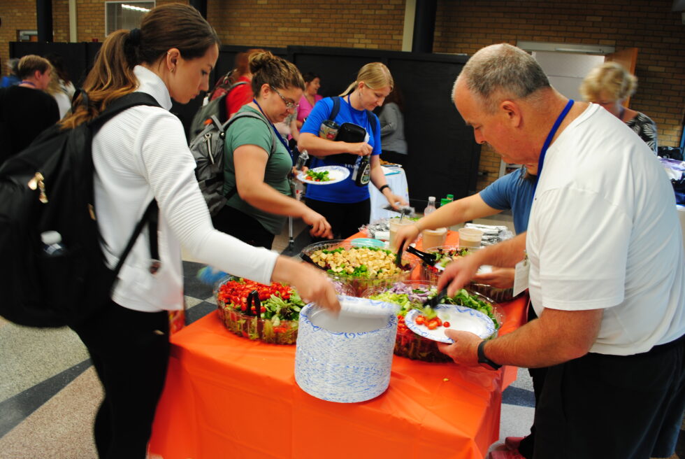 People serving themselves food from a buffet table at an event.