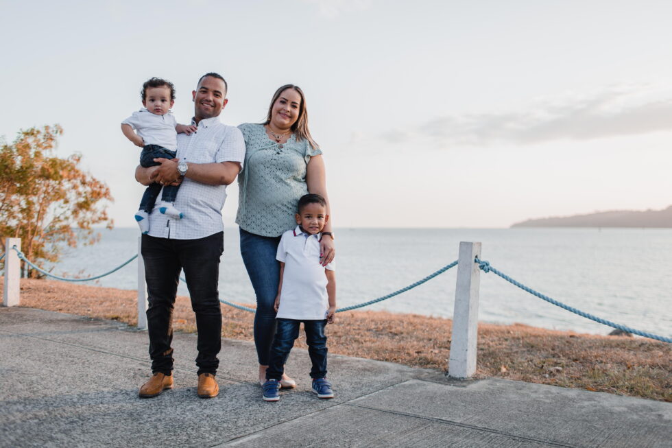 A family of four standing by a waterfront, smiling and enjoying the view.
