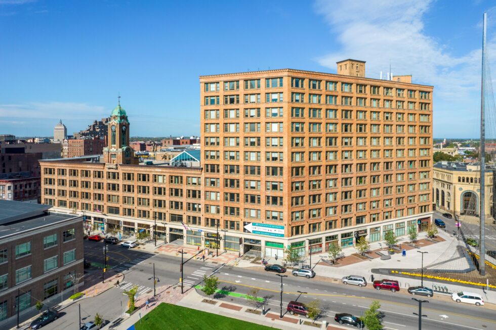 Large orange brick building under a clear blue sky in an urban setting.